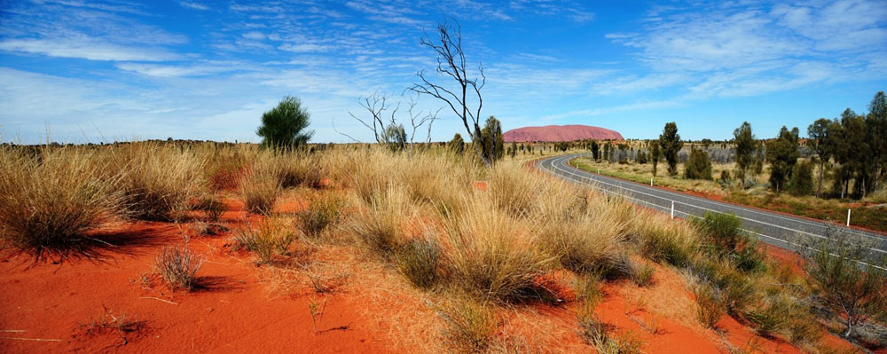 Strasse mit Uluru im Hintergrund