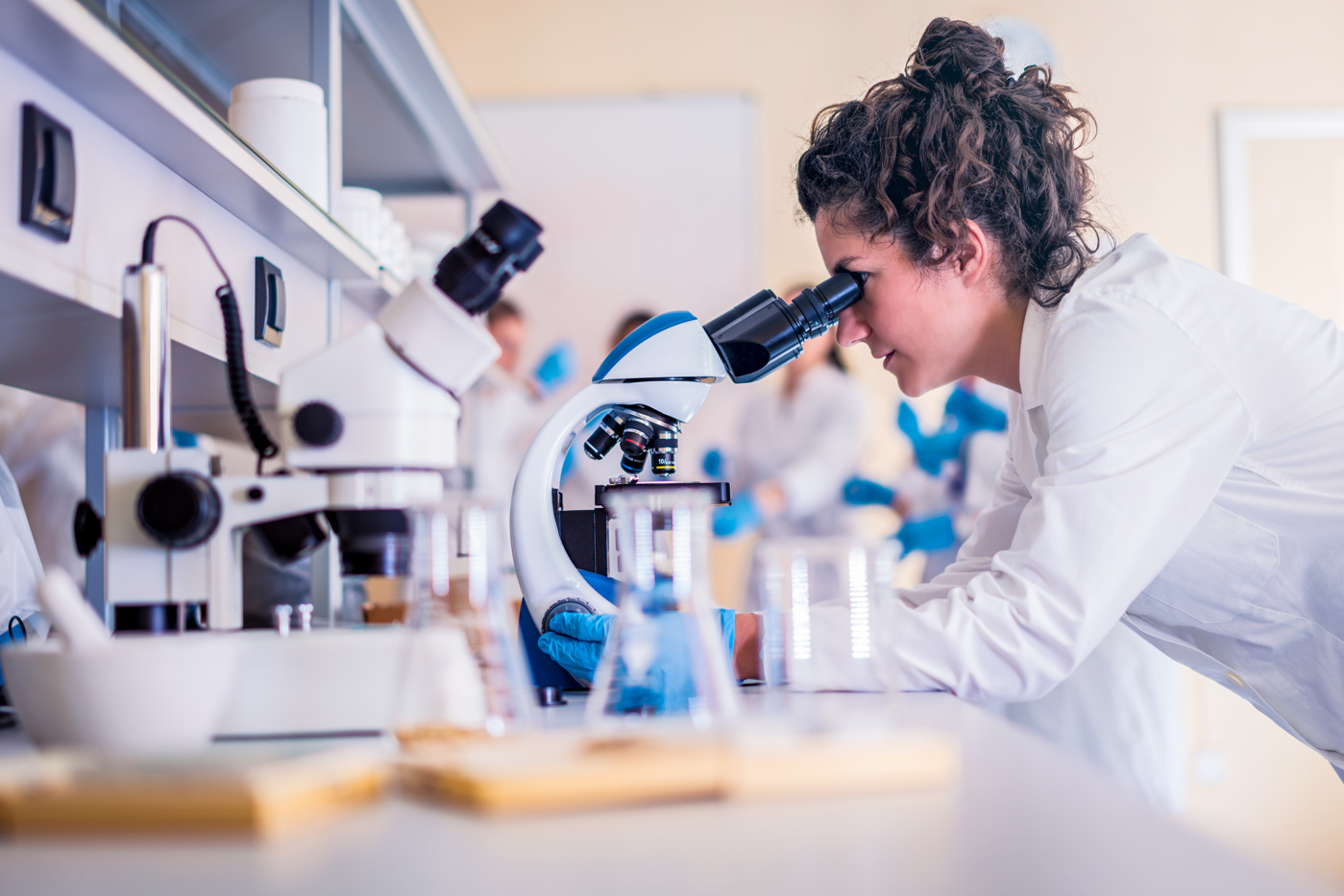 Une technicienne en analyses biomédicales ES analyse un échantillon de tissu au microscope.