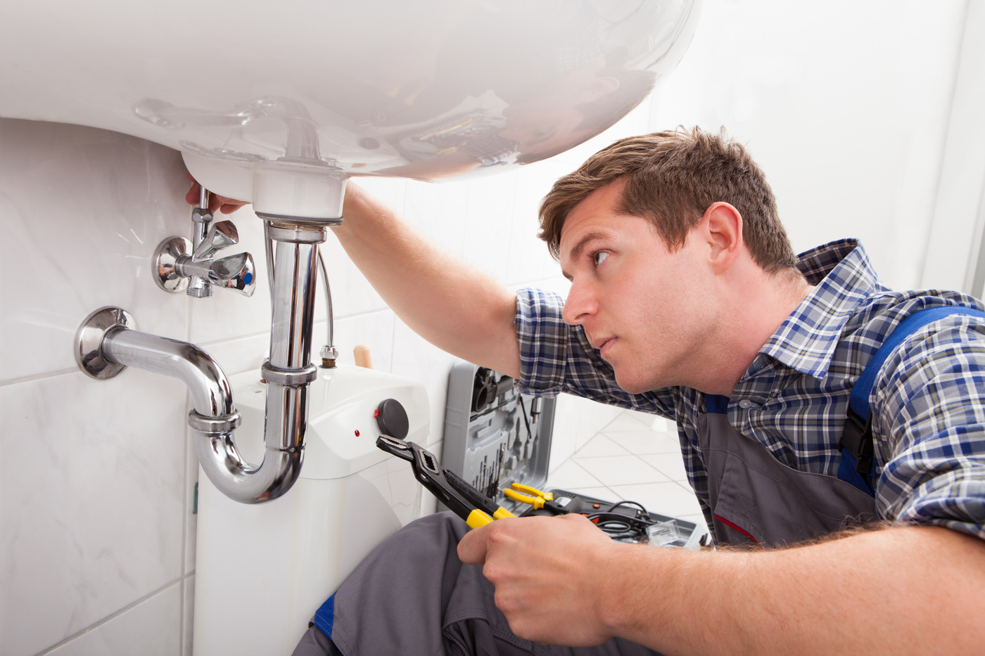 A head plumber installs a washbasin in a customer's bathroom.