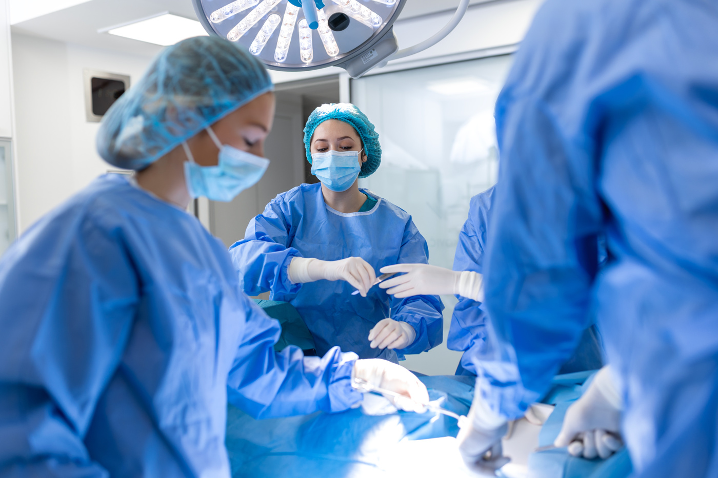 Une technicienne en salle d'opération ES tend le scalpel au chirurgien.