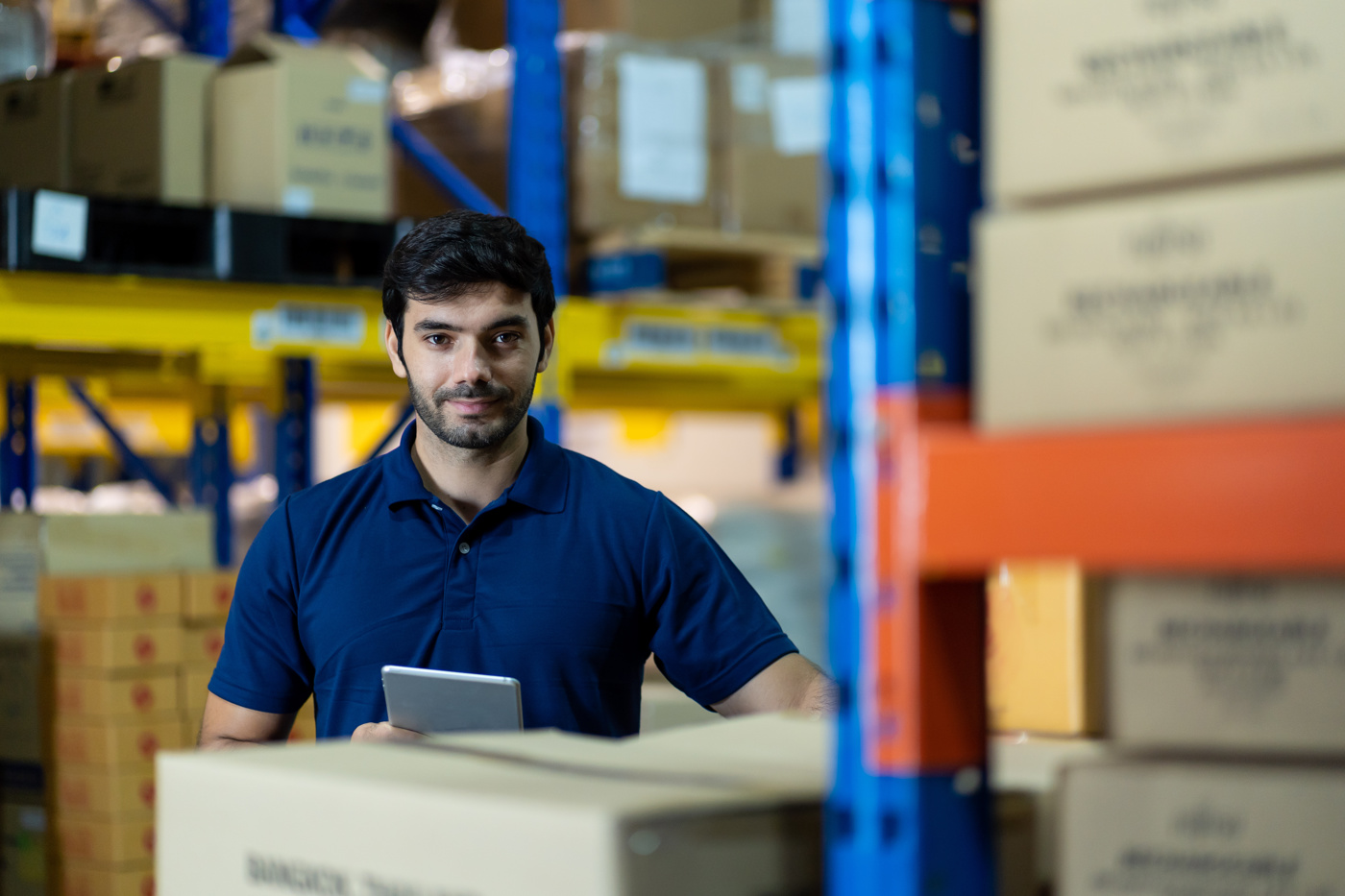 Un spécialiste en logistique avec brevet fédéral se tient dans l'entrepôt pour trouver des mesures d'optimisation possibles dans les processus logistiques internes à l'entreprise.