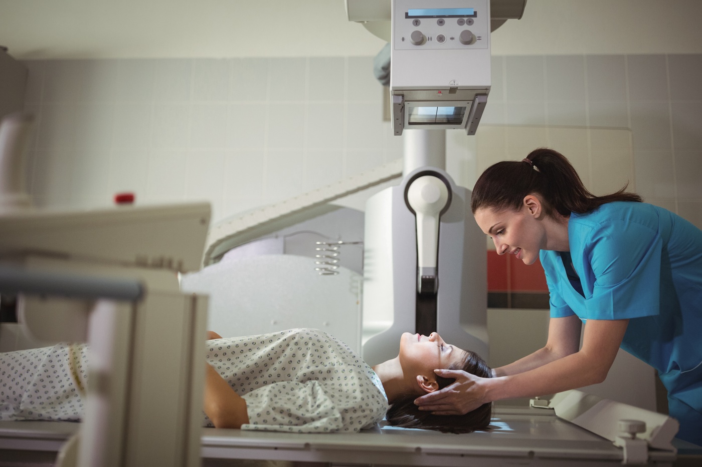 Eine Radiologiefachfrau HF platziert den Kopf einer Patientin korrekt unter dem Röntgengerät.